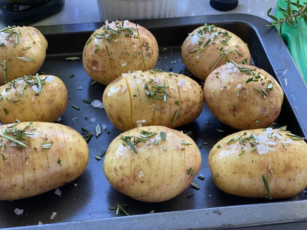 Hasselback potatoes sprinkled with salt and rosemary ready to bake